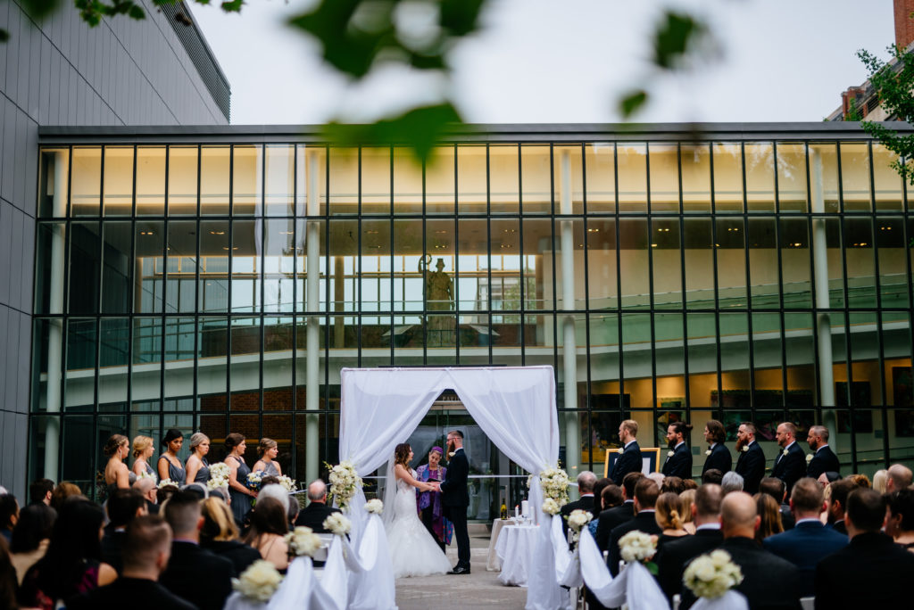 A bride and groom stand at the alter of a wedding ceremony in the courtyard. 