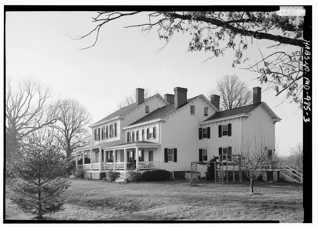 Black and white photograph of a white house with two telescoping additions, gabled roofs, and five chimneys.