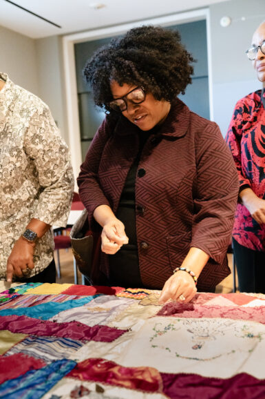 A photo of a woman looking over a crazy quilt