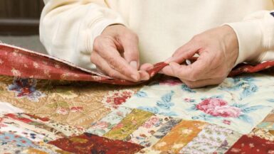 A photo of hands sewing a quilt